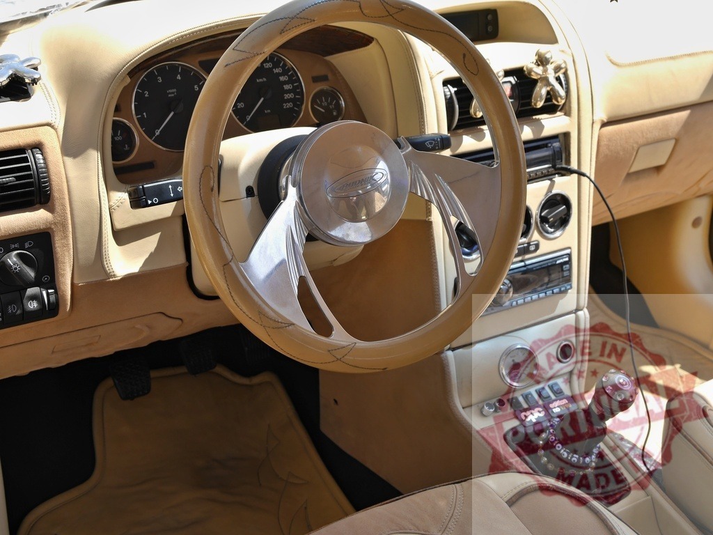 Custom car interior showing beige leather and dashboard | Beige custom car interior featuring a unique steering wheel, dashboard, and gear shifter - Realized with Pictrs.com