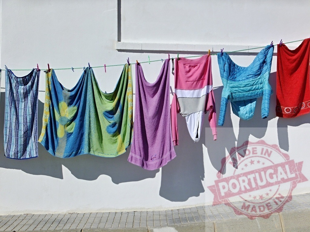 Colorful laundry drying on clothesline in sunlight | Colorful laundry hanging on a clothesline against a white wall with shadows - Realized with Pictrs.com