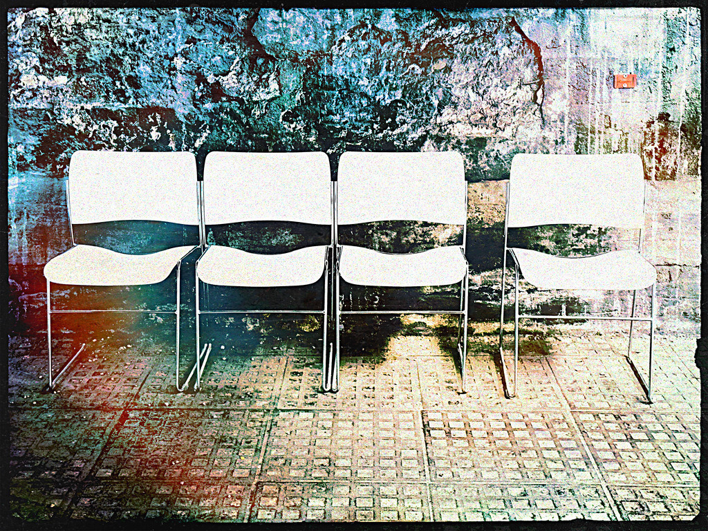 Zeitlose Wartezone | Dieses eindrucksvolle Foto fängt den Moment des Innehaltens und der Erwartung ein. Vier minimalistisch gestaltete, leere Stühle stehen in Reih und Glied vor einer markanten, verwitterten Wand mit abwechslungsreicher Struktur und Farbverläufen. Die Komposition symbolisiert Warteschleifen, Ungewissheit und die Ruhe vor dem nächsten Ereignis. Ideal für moderne Raumgestaltung, Büros oder Wartebereiche – schaffen Sie eine Atmosphäre, die zum Nachdenken anregt und dennoch klar und aufgeräumt wirkt. - Realisiert mit Pictrs.com