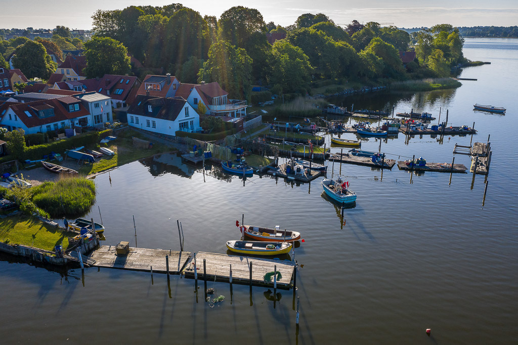 zeitenwende-farbe-01-02 | Luftaufnahme der Fischersiedlung Holm in Schleswig an der Schlei. Das Bild entstand kurz nach Sonnenaufgang. An den Brücken sind die offenen Motorboote der Holmer Fischer zu erkennen. - Realisiert mit Pictrs.com