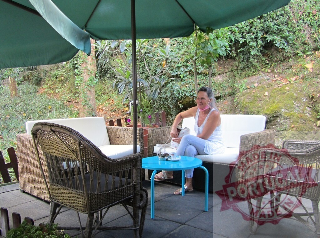 Woman relaxing on modern wicker patio furniture outdoors | Woman sitting on outdoor modern wicker furniture enjoying a green garden patio - Realisiert mit Pictrs.com