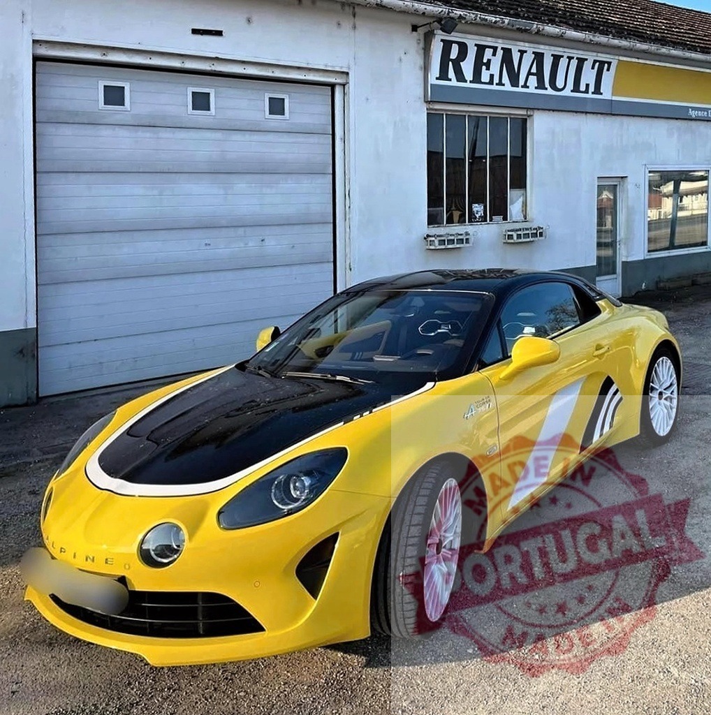 Alpine A110 Tour de Corse 75 in front of Renault dealership | Yellow Alpine A110 sports car with black hood parked at a Renault garage - Realisiert mit Pictrs.com