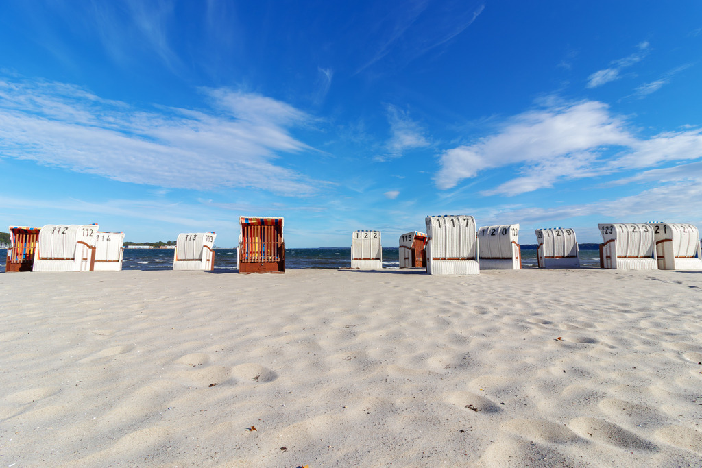 Wandbild: Strandkörbe unter weitem Himmel – Eckernförde ganz ruhig | Dieses Wandbild zeigt den Sandstrand von Eckernförde an der Ostsee. Eine Reihe weißer Strandkörbe steht geordnet auf dem hellen Sand, ausgerichtet zum Meer. Der Himmel ist weit und leicht bewölkt, das Wasser ruhig und tiefblau. Die Szene vermittelt norddeutsche Klarheit, Ordnung und Gelassenheit – ein Moment, der den Rhythmus des Küstenalltags einfängt. Ideal als Wandbild für maritime Wohnkonzepte – ob als Leinwandbild, Acrylglasbild, Alu-Dibond FineArt Print oder als Akustikbild. Ein stiller, strukturierter Akzent für Wohnzimmer, Büro oder Ferienwohnung. - Realisiert mit Pictrs.com