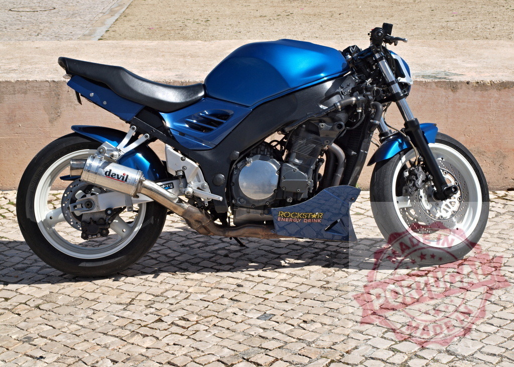 Blue streetfighter custom motorcycle with white wheels | Blue custom streetfighter motorcycle with Devil exhaust and Rockstar Energy Drink sticker parked on cobblestones - Realisiert mit Pictrs.com