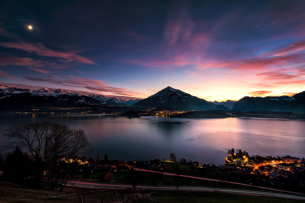 Gunten | Langzeitaufnahme der Aussicht von Sigriswil über den Thunersee zu den Berner Alpen im Abendrot. Imposant ist der Niesen aus dieser Perspektive mit einer hübschen Spiegelung im See. Im Vordergrund ist Gunten und am unteren Rand Lichtspuren von Autos auf der Strasse von Gunten nach Sigriswil. 
-----------------------------------------------
Long exposure of the view from Sigriswil over Lake Thun to the Bernese Alps in the afterglow. The Niesen is imposing from this perspective with a pretty reflection in the lake. Gunten is in the foreground and lighttrails from cars on the road from Gunten to Sigriswil at the bottom.
-----------------------------------------------
Dieser Druck ist in einer limitierten Auflage von 5 Exemplaren erhältlich. 
This print is available in a limited edition of 5 copies. 
http://art.hess.photography/81-gunten.html - Realisiert mit Pictrs.com