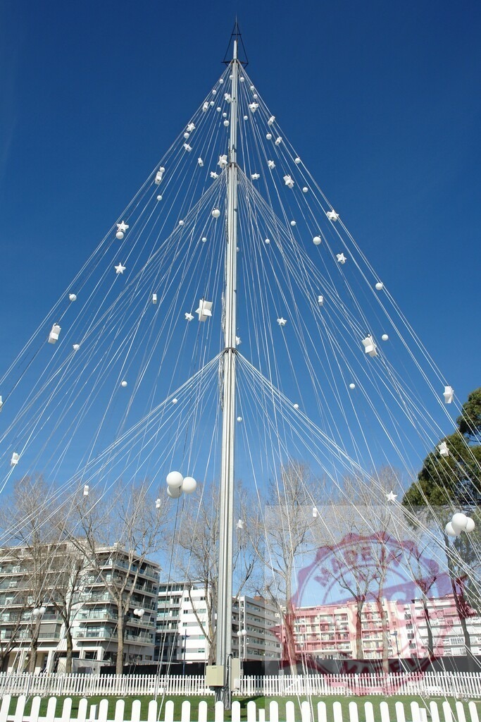 Modern Christmas tree decoration with white ornaments in urban park | Contemporary Christmas tree with white ornaments creating a festive display under a clear blue sky - Realized with Pictrs.com