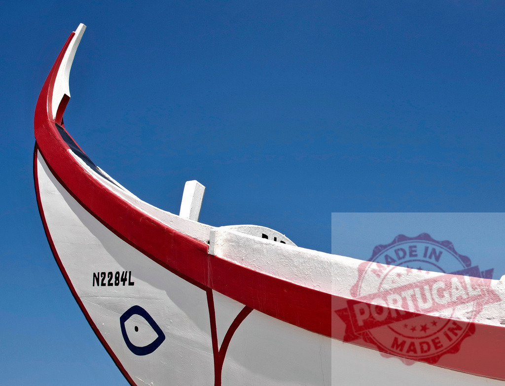 Traditional Portuguese fishing boat prow with blue eye | Traditional Nazare fishing boat prow against a clear blue sky, featuring a red stripe and a painted eye - Realisiert mit Pictrs.com