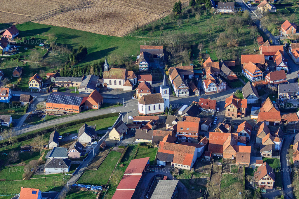Aerial view: Village with Catholic Church of Saint George and Protestant Church of the South in Keffenach in the state Bas-Rhin, France. – Photo: IMG_38758.jpg taken on 03/20/2011 by Werner Riehm/FLY-FOTO.com – Resolution of the original: 4400 x 2934 px