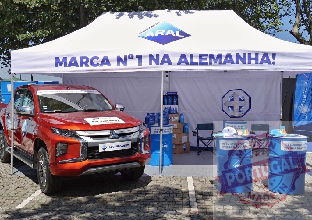 Aral lubricants promoting their products with Mitsubishi pickup truck at outdoor event | Aral, the German lubricant brand, showcasing their products alongside a Mitsubishi L200 pickup truck at an outdoor promotional event - Realized with Pictrs.com