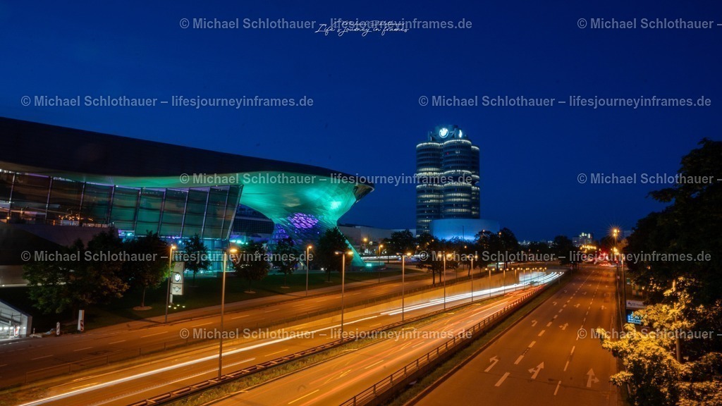 BMW Museum und BMW Welt bei Nacht | Die markante Architektur von BMW Museum und BMW Welt leuchtet bei Nacht, Lichtspuren vorbeifahrender Autos ziehen sich Ã¼ber die StraÃŸe. - Realisiert mit Pictrs.com