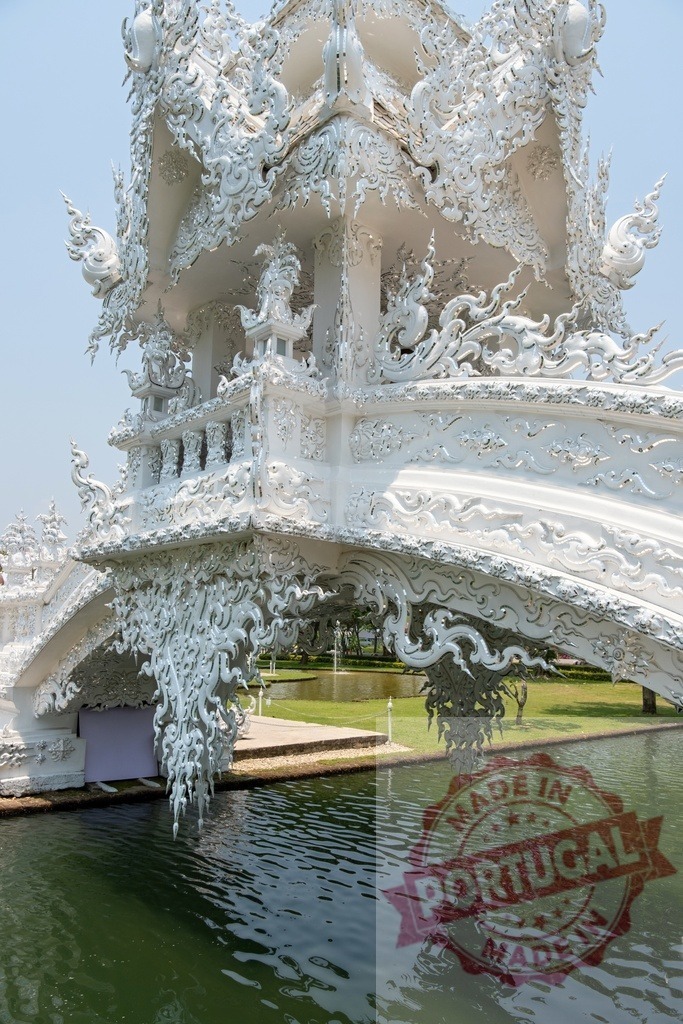 Ornate white bridge crossing over water in Wat Rong Khun, Thailand | Low angle view of a highly decorated white bridge over calm water in Wat Rong Khun, Chiang Rai, Thailand - Realized with Pictrs.com