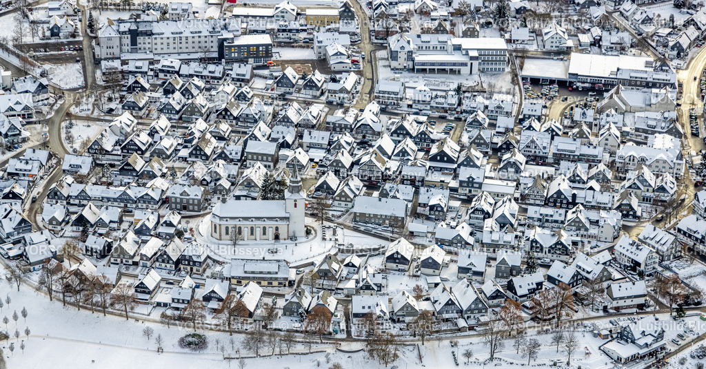 Winterberg221201442 | Luftbild Innenstadt mit kath. Kirche St. Jakobus der Ältere, schneebedeckte Häuser, Winterwunderland in Winterberg im Sauerland, am Kahlen Asten und den Skiabfahrten und dem Skilift-Karussell Winterberg, Winterberg, Sauerland, Nordrhein-Westfalen, Deutschland