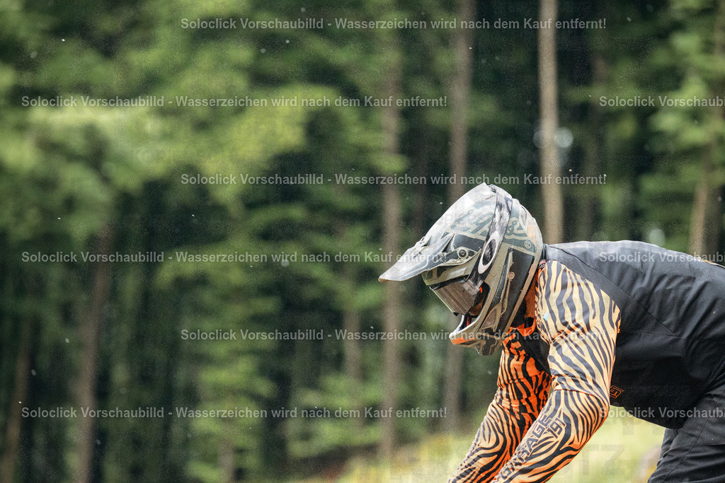 Ausgezeichnete Fahrt | Das Bild zeigt einen Mountainbiker, der nach einer Fahrt auf einen Baum gelehnt ist. Er trägt einen Helm der Marke Oakley und eine Schutzbrille. Sein Trikot hat ein auffälliges Tiger-Muster. Der Hintergrund besteht aus dichtem Grünwald, was auf eine Fahrt im Gelände hindeutet. - Realisiert mit Pictrs.com