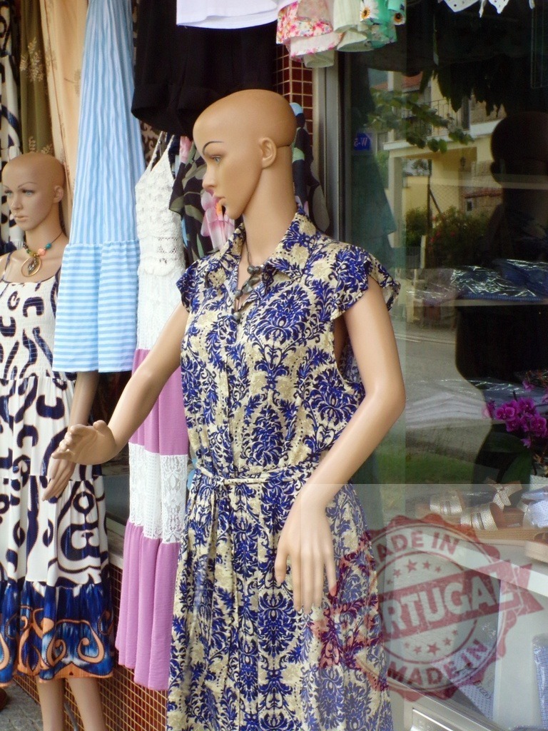 Mannequins displaying fashion dresses in clothing store window | Mannequins displaying patterned summer dresses and apparel in a retail boutique window - Realized with Pictrs.com
