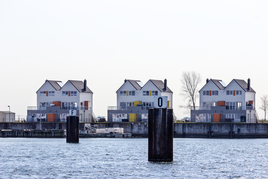 Wandbild: Ferienwohnungen in Olpenitz | Dieses Wandbild im Querformat zeigt einige Ferienwohnungen direkt am Meer in Olpenitz. Neben dem rechten Ferienhaus sind zwei winterliche Bäume zu sehen.  - Realisiert mit Pictrs.com