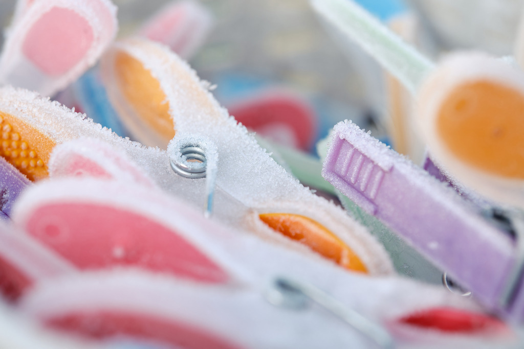 bunte Wäscheklammern mit Eiskristallen | Austria - January 14, 2024: Bunte Wäscheklammern mit Eiskristallen in einem Beutel. - Realisiert mit Pictrs.com