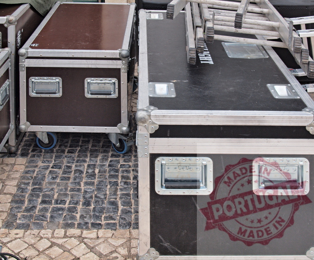 Flight cases and aluminum ladders laying on cobblestone street | Flight cases and aluminum ladders laying on cobblestone street, ready for event setup - Realisiert mit Pictrs.com