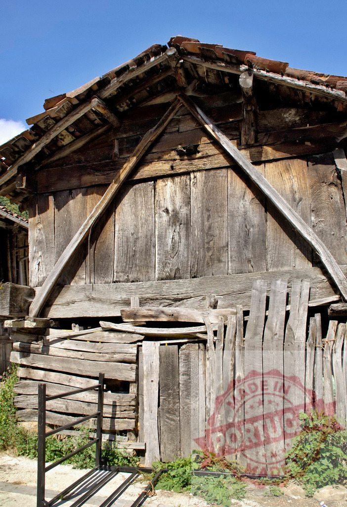 Weathered old wooden barn architecture in countryside | Old traditional farm building with rustic wooden planks and a tiled roof under a blue sky - Realized with Pictrs.com