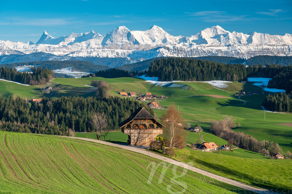 traditional Bernese farmhouse called Stöckli in front of the mighty Bernese Alps in spring | Die ideale Geschenkidee für Naturliebhaber. Naturbilder von Marcel Gross Photography für ihr Zuhause in den verschiedensten Formaten und Materialien. - Realisiert mit Pictrs.com