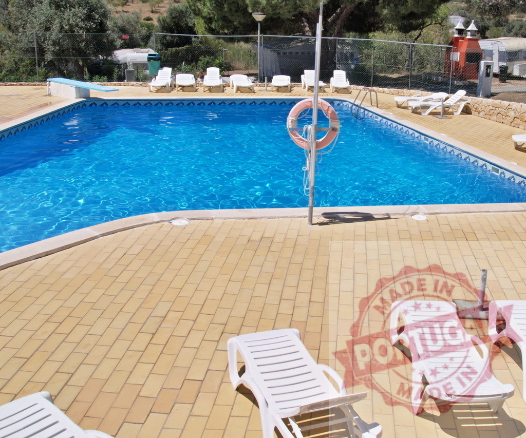 Swimming pool with sun loungers for summer relaxation | Outdoor swimming pool with blue water and empty white lounge chairs on a sunny day - Realisiert mit Pictrs.com