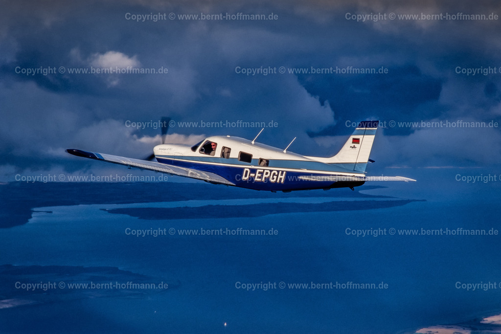 PLBDD_air2air_PiperSara_06_90x60 | Luftbild. Einmotoriges Geschäftsflugzeug Typ " PIPER Saratoga II TC " unterhalb einer Wolkenschicht. Sonnenstrahlen erhellen die Szenerie. Flug über der Flensburger Außenförde. ___ Das Foto ist eine Reproduktion von einem Farbdia. - Realisiert mit Pictrs.com