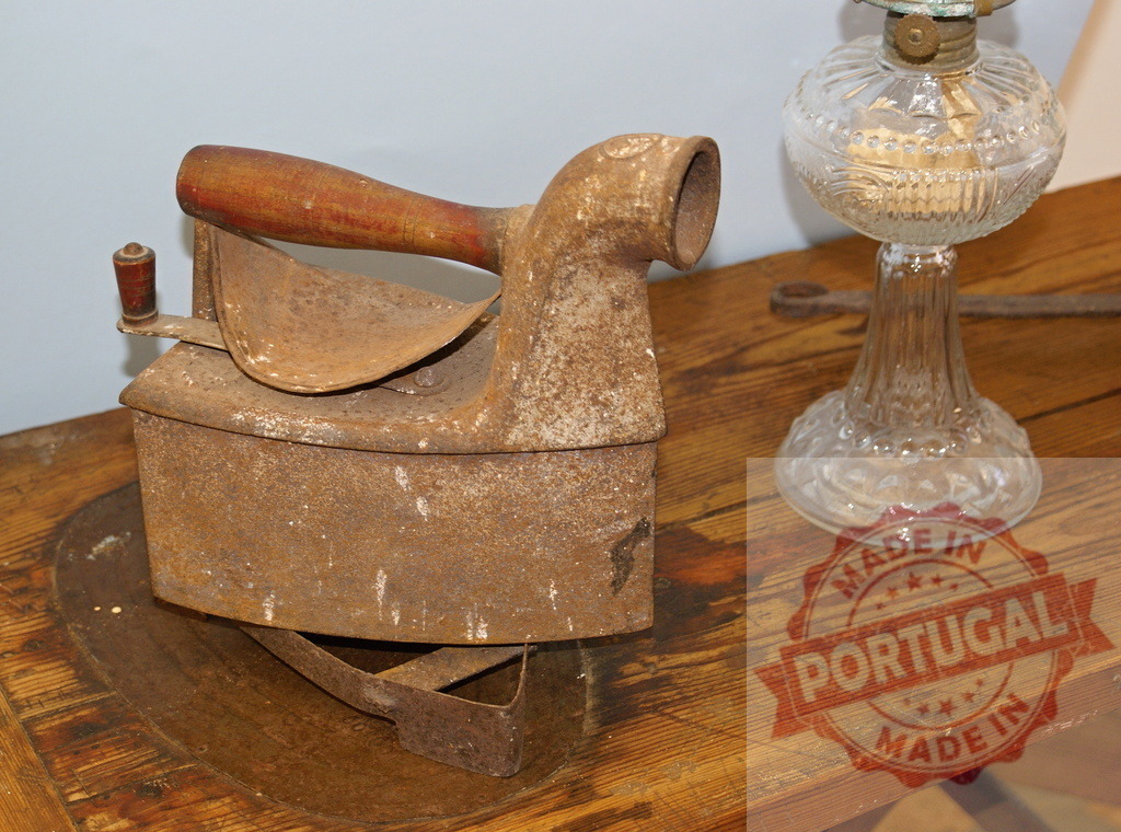 Antique charcoal iron and oil lamp on rustic wood table | Rusty charcoal iron and vintage oil lamp on a textured wooden table, representing history - Realized with Pictrs.com