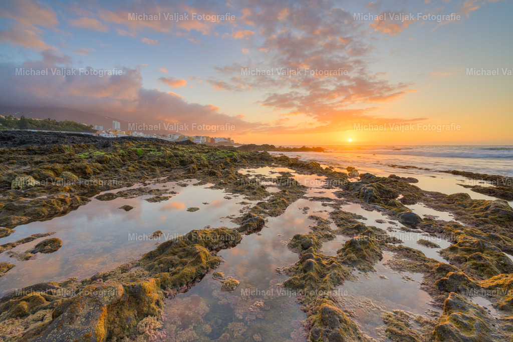 Am Playa Jardin in Puerto de la Cruz | Der Sonnenuntergang am Playa Jardin in Puerto de la Cruz ist ein atemberaubendes Naturschauspiel. Die malerische Kulisse des schwarzen Strandes, umgeben von üppigen Gärten und dem majestätischen Teide im Hintergrund, bietet einen unvergesslichen Anblick, wenn die Sonne hinter dem Horizont versinkt. Die warmen Farben des Himmels spiegeln sich im Atlantik und schaffen ein perfektes Ambiente für einen entspannten Abend. Es ist ein Moment, der zum Innehalten und Genießen einlädt, während die letzten Sonnenstrahlen den Tag verabschieden. - Realisiert mit Pictrs.com