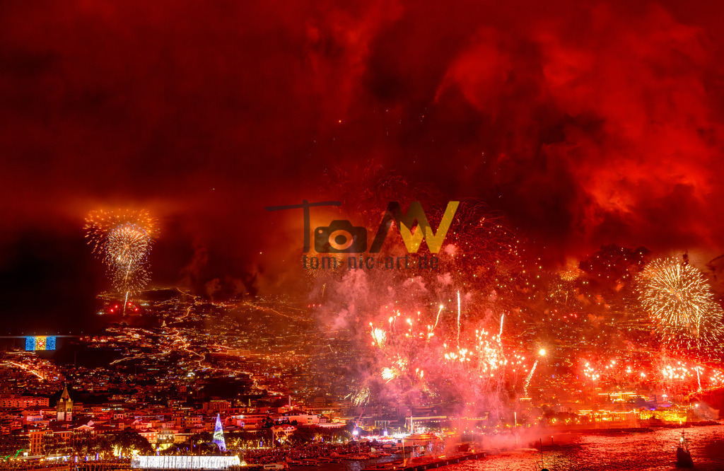 Rot leuchtendes Feuerwerk an Silvester auf Madeira, Funchal | Das Bild zeigt das berühmte Silvester-Feuerwerk in Funchal, Madeira. Es gilt als eines der größten Feuerwerke der Welt. Das Spektakel findet über der Bucht von Funchal statt, die wie ein Amphitheater geformt ist. Die Pyrotechnik wird von 59 verschiedenen Stationen rund um die Hauptstadt gezündet. Das Feuerwerk dauert etwa acht Minuten und kostet die Insel rund eine Million Euro pro Jahr.  - Realisiert mit Pictrs.com