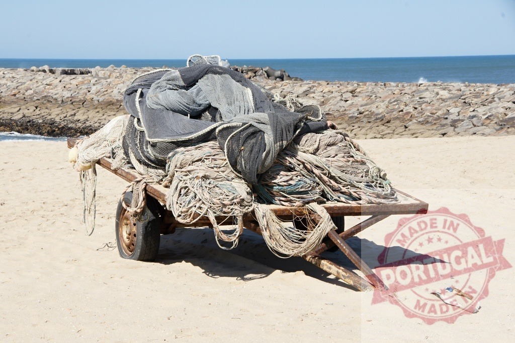 Rusty cart carrying fishing nets on sandy beach | Fishing nets piled on a rusty cart on a sandy beach by the ocean - Realisiert mit Pictrs.com