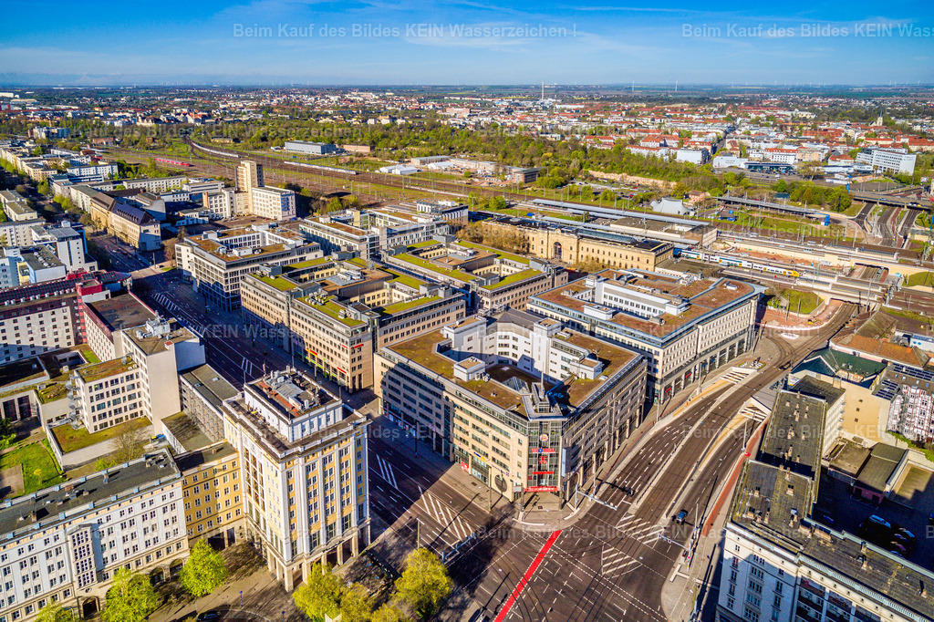 Magdeburg neuer Tunnel CityCarre-0021 | Diese Luftaufnahme zeigt einen weiten Blick über die Magdeburger Innenstadt in Richtung Hauptbahnhof. Zwischen der Otto-von-Guericke-Straße und der Ernst-Reuter-Allee erstrecken sich große Büro- und Geschäftshäuser, breite Straßen und weitläufige Verkehrsanlagen. Im oberen Bildbereich sind die Gleisanlagen des Hauptbahnhofs zu erkennen. Die Aufnahme verdeutlicht, wie eng die Innenstadt mit dem Bahnverkehr verbunden ist. –  – Das Stadtbild ist in diesem Bereich stark vom Wiederaufbau nach dem Zweiten Weltkrieg geprägt. Großzügig angelegte Straßenräume und großflächige Gebäudekomplexe unterscheiden sich deutlich von den kleinteiligeren historischen Straßenzügen anderer Innenstadtbereiche. Gleichzeitig treffen unterschiedliche Architekturepochen aufeinander: ältere Gebäude stehen neben späteren Neubauten und modernen Bürohäusern. –  – Aus der Vogelperspektive werden die Struktur und die Dimensionen dieses zentralen Stadtbereichs besonders gut sichtbar. Das Luftbild hält einen Ausschnitt der Magdeburger Stadtentwicklung fest und zeigt eine Innenstadt, die sich über Jahrzehnte verändert hat und bis heute im Wandel bleibt. –  – Wer Magdeburg kennt, entdeckt hier vertraute Straßen und Gebäude aus einer ungewohnten Perspektive. Als hochwertiges Wandbild oder Leinwand bringt diese Luftaufnahme ein Stück Magdeburger Stadtgeschichte nach Hause oder in Geschäftsräume – für alle, die sich mit der Landeshauptstadt verbunden fühlen. - Realisiert mit Pictrs.com
