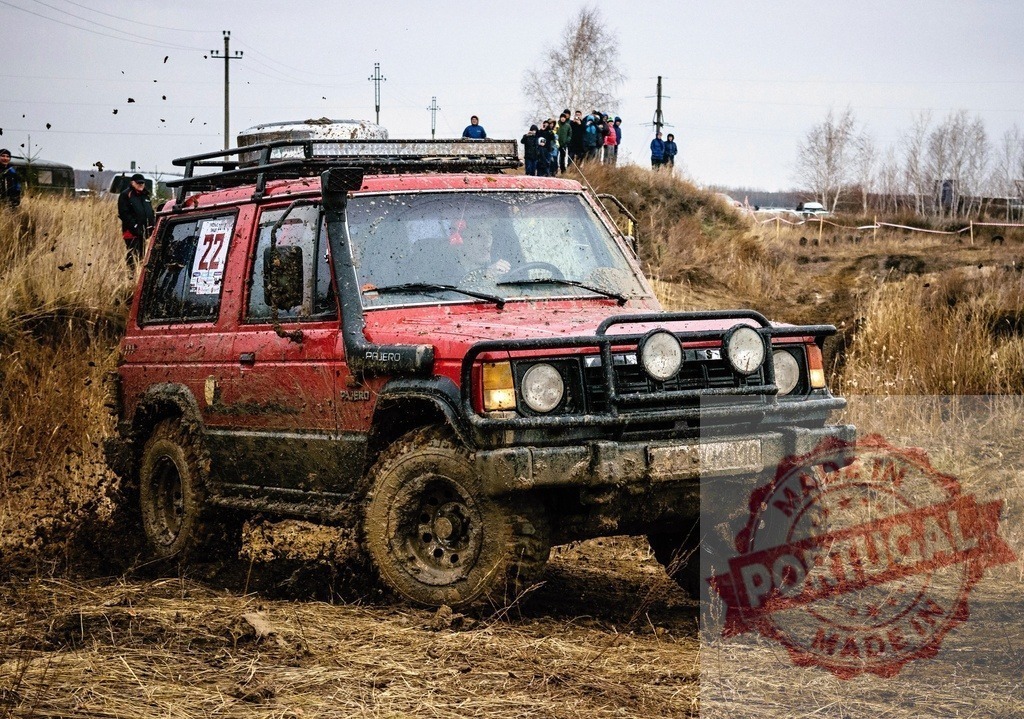 Red Mitsubishi Pajero SUV off-roading through mud | Red Mitsubishi Pajero SUV driving through a muddy track during an off-road rally event - Realisiert mit Pictrs.com