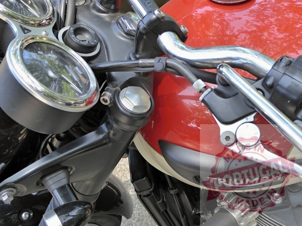 Triumph motorcycle detail showing handlebar, dials, and fuel tank | Close-up of a Triumph motorcycle, highlighting the handlebar, instrument dials, and fuel tank - Realized with Pictrs.com