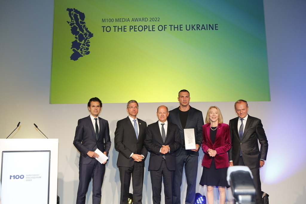 M100 Media Award: „Preis der europäischen Presse“ in Potsdam für das Ukrainische Volk verliehen. | Mit dem M100 Media Award, der sich als „Preis der europäischen Presse“ versteht, wird in diesem 
Jahr das Ukrainische Volk ausgezeichnet. Die Auszeichnung nimmt stellvertretend Wladimir 
Klitschko in der Orangerie im Park Sanssouci entgegen. Das Bild zeigt Mike Schubert, Olaf Scholz,Wladimir Klitschko, US-Botschafterin Amy Gutmann und Donald Tusk.