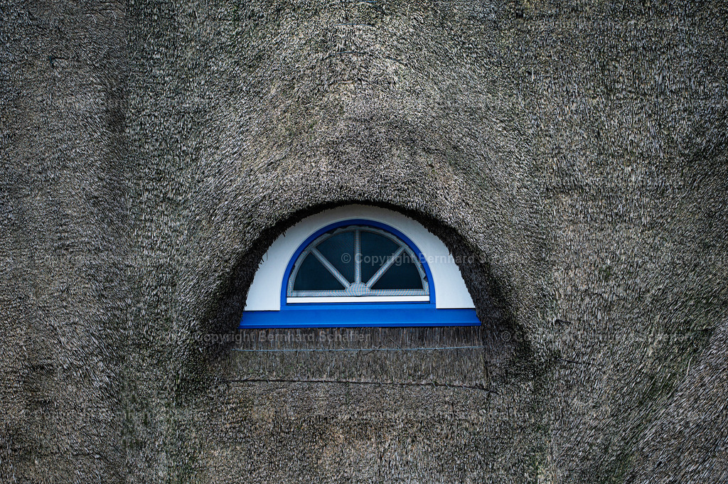 Dachfenster im Reetdachhaus | Ein halbrundes Fenster im Dach eines Reetdachhauses in Deutschland. - Realisiert mit Pictrs.com