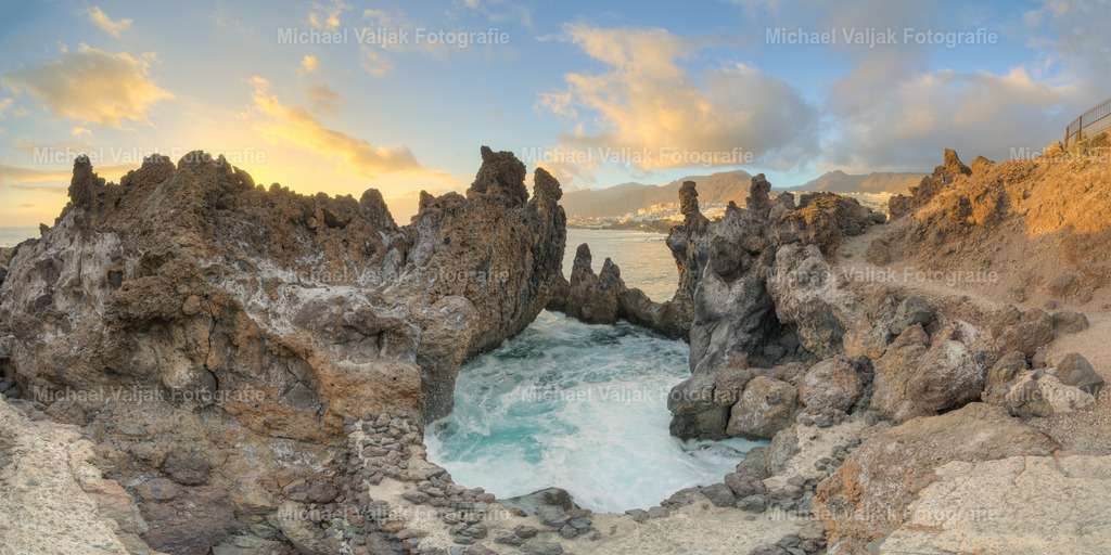 Charco del Diablo Panorama | Charco del Diablo, ein verstecktes Juwel auf Teneriffa, ist bekannt für seine einzigartigen Lava-Felsformationen und natürlichen Schwimmbecken, die eine atemberaubende Kulisse für Panoramaaufnahmen bieten. Diese natürlichen Pools, die inmitten der schwarzen Lavasteine liegen, sind ein Meisterwerk der Natur und bieten eine ruhige Oase abseits der ausgetretenen Touristenpfade. Besucher können die spektakuläre Aussicht auf Puerto de Santiago genießen, während sie von der beeindruckenden Landschaft umgeben sind. Es ist ein idealer Ort für diejenigen, die Ruhe und Natur suchen. - Realisiert mit Pictrs.com