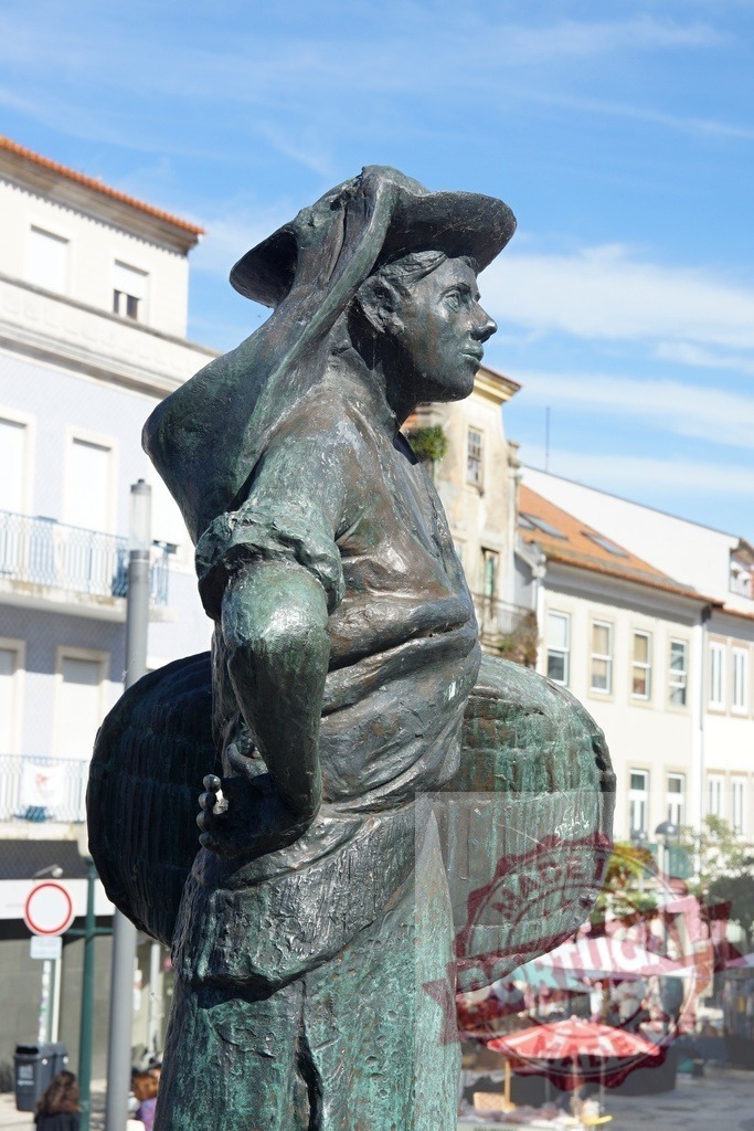 Bronze statue of a woman carrying baskets in Aveiro, Portugal. Aveiro - Portugal | Bronze statue depicting a traditional woman carrying three baskets, representing the local Ovos Moles sellers - Realized with Pictrs.com