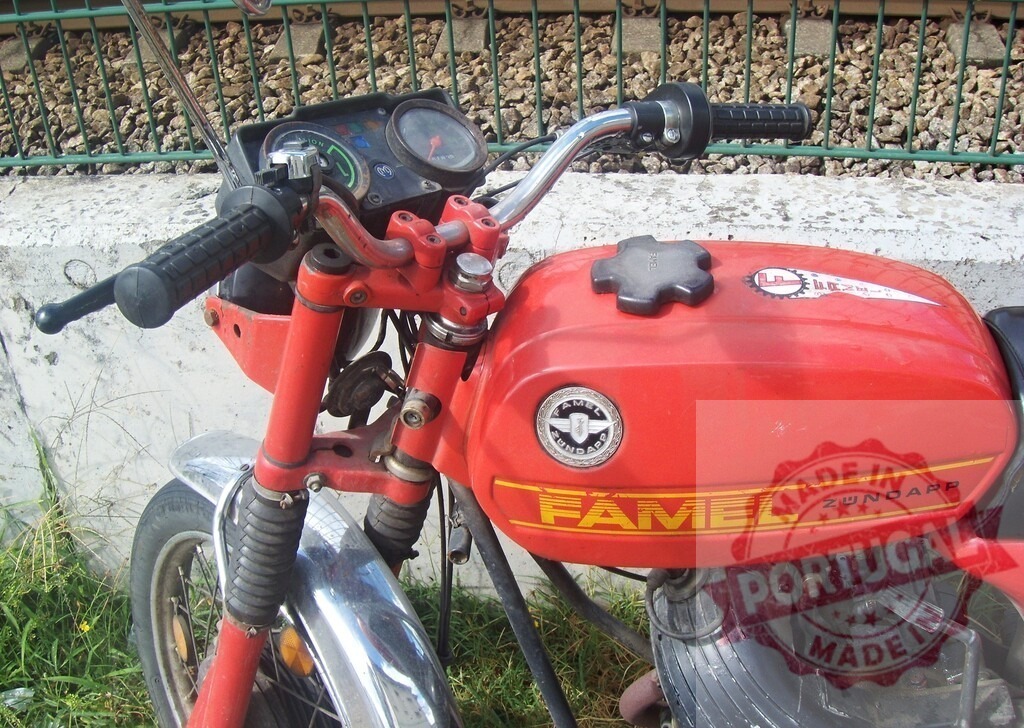 Red Famel Zundapp Motorcycle Parked near Railroad Tracks | Close-up of a vintage red Famel Zundapp motorcycle parked near railroad tracks, showcasing its design and branding - Realized with Pictrs.com