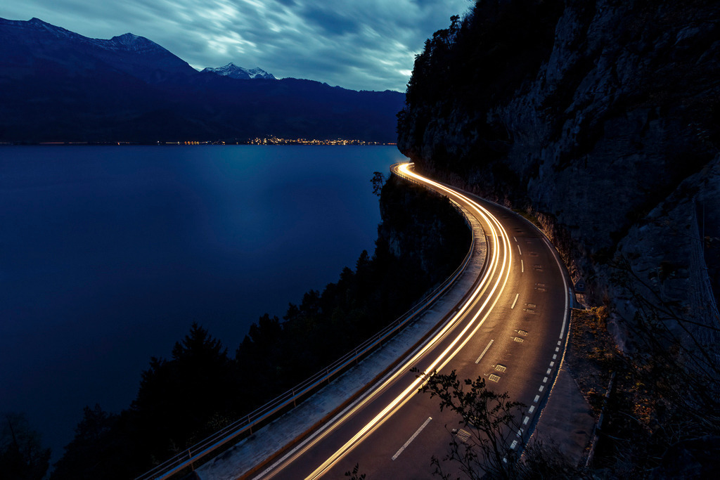 Lighttrails am Thunersee | Lichtspuren schlängeln sich entlang des Thunersees durch die nächtliche Berglandschaft. Die Langzeitbelichtung fängt die Bewegung ein und kontrastiert sie mit der Ruhe des Sees und der Dunkelheit der Alpen – ein Bild voller Dynamik und Tiefe. - Realisiert mit Pictrs.com
