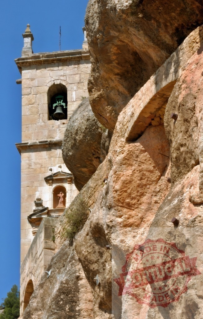Church bell tower emerging from a rocky cliff | Ancient church building integrated within natural rock formations under a clear blue sky - Realisiert mit Pictrs.com