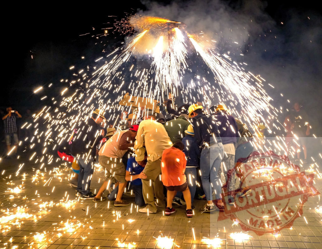 Correfoc festival celebrating fiery tradition with sparks | People participating in the Correfoc traditional fire-run festival, showered with fireworks sparks at night - Realisiert mit Pictrs.com