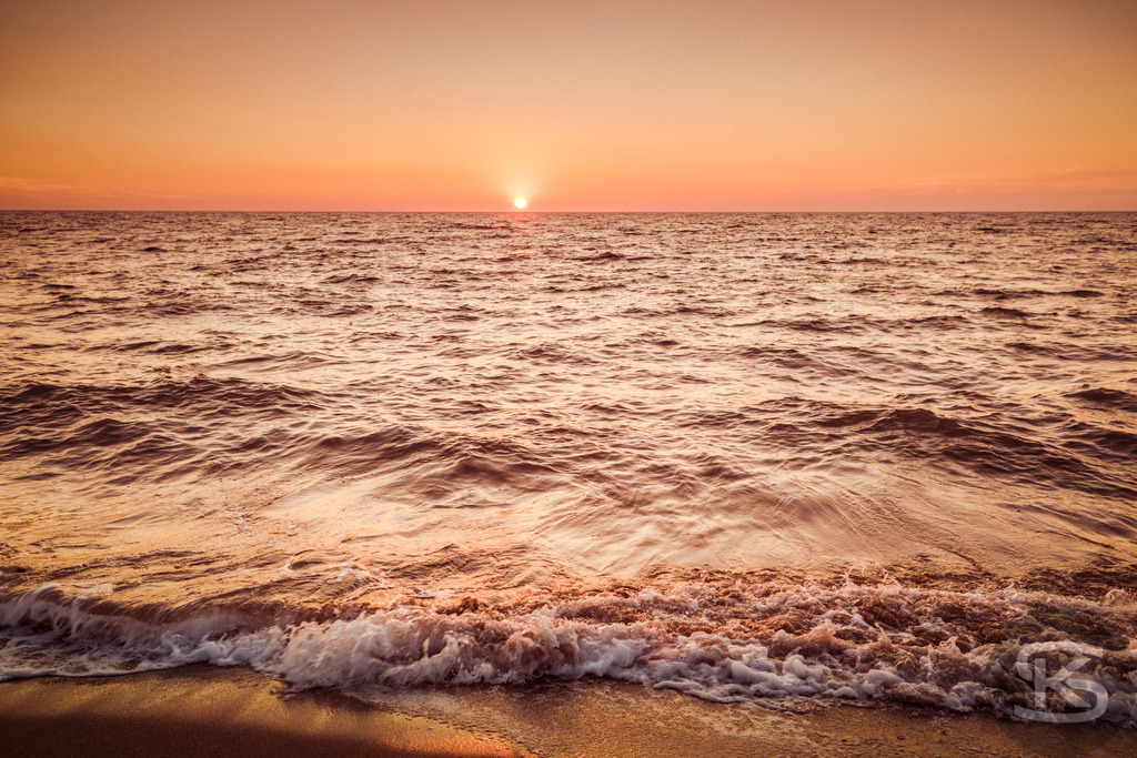 Goldener Sonnenuntergang über den Meereswellen am Strand | Erleben Sie die magische Atmosphäre eines goldenen Sonnenuntergangs über dem Meer. Das Bild fängt die sanften Wellen ein, die am sandigen Strand brechen, während die untergehende Sonne den Himmel in warmes Orange und Gelb taucht. Eine friedliche und idyllische Szene, die an einen entspannten Urlaub erinnert. - Realisiert mit Pictrs.com