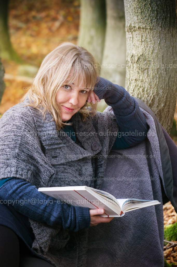 Woman reads calmly in autumn scenery | 40 jährige blonde Frau im Herbstwald. Sie macht ein Picknick und entspannt sich mit einem Buch. Strickkleidung mit Poncho und Rock.