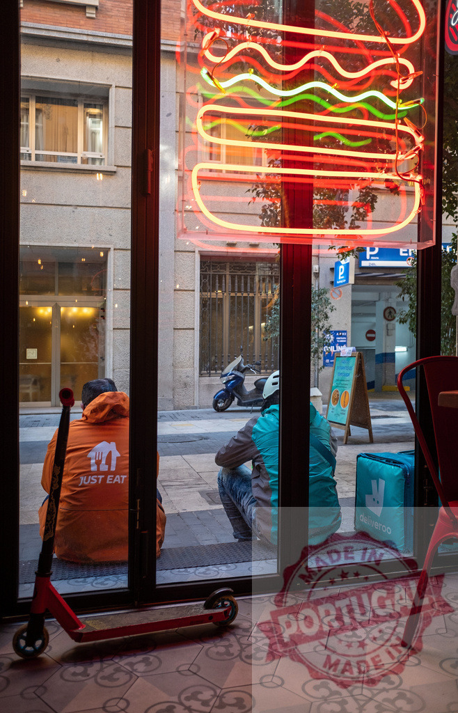 Food delivery drivers waiting outside restaurant at night | Delivery couriers for Just Eat and Deliveroo wait outside a fast food restaurant under a neon sign - Realisiert mit Pictrs.com