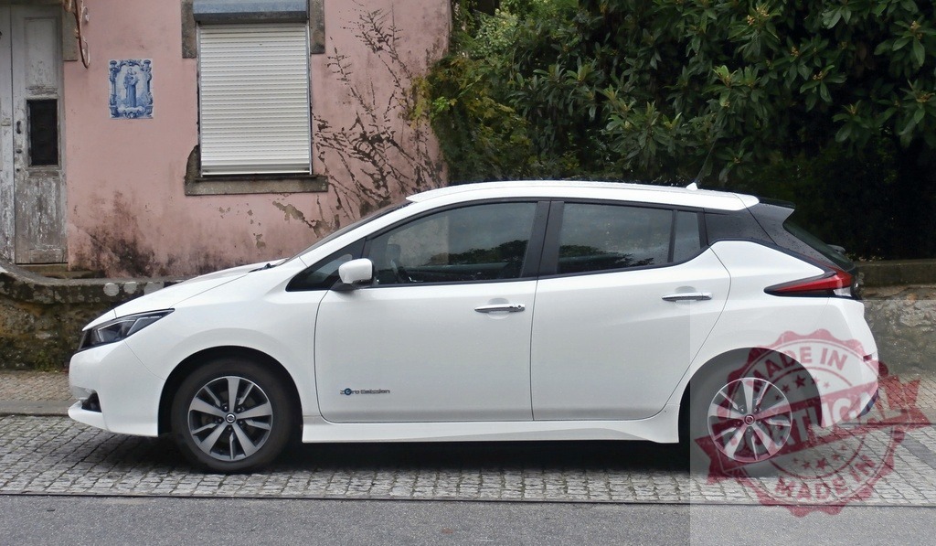 White Nissan Leaf electric car parked on street | Nissan Leaf electric vehicle parked on a cobblestone street, fostering sustainable urban mobility - Realized with Pictrs.com