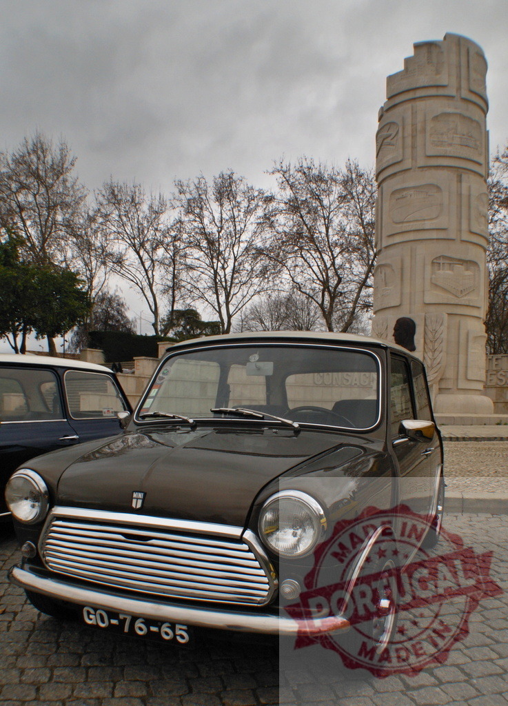 Classic Mini Cooper parked near Padrão dos Descobrimentos in Lisbon | Brown vintage Mini Cooper is parked in a square in Lisbon, with Padrão dos Descobrimentos monument in the background - Realized with Pictrs.com