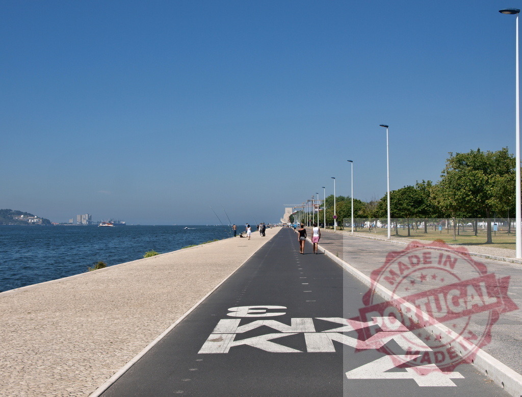 People exercising along Tagus River promenade in Lisbon. Lisbon - Portugal | People enjoying leisure activities along the waterfront promenade next to the Tagus River - Realized with Pictrs.com