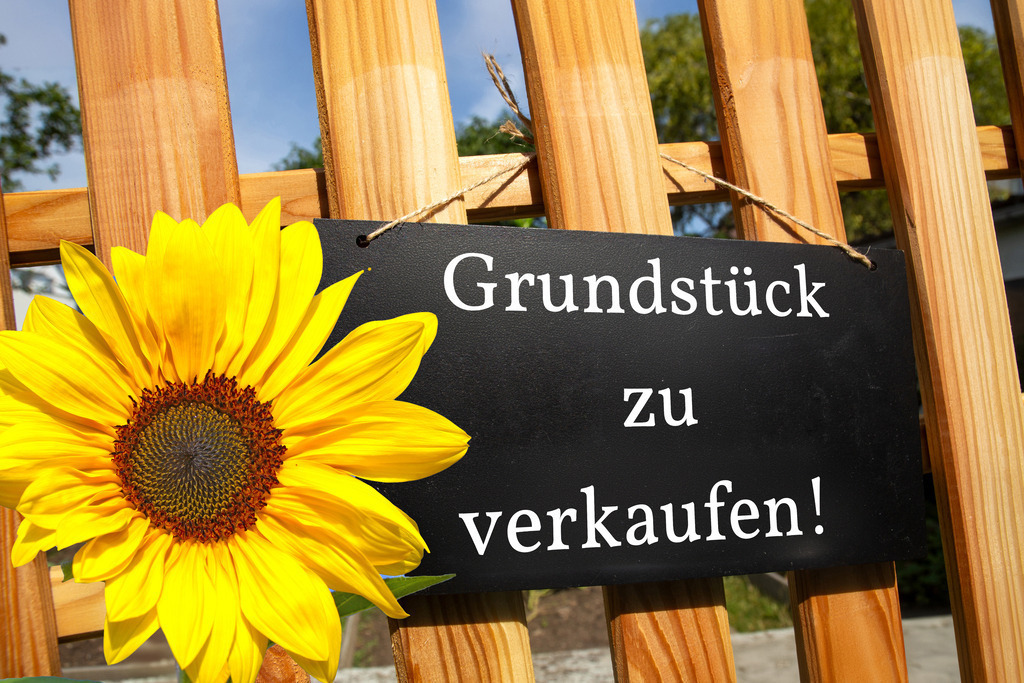 Grundstück zu verkaufen Vorlage / Schild: Schild mit der Aufschrift GRUNDSTÜCK ZU VERKAUFEN an einem Holzzaun | Professionelle Grußkarten und Symbolbilder für Unternehmen: Feiertage, Mitarbeitersuche, Betriebsferien & Events – perfekt für Web & Social Media. - Realisiert mit Pictrs.com