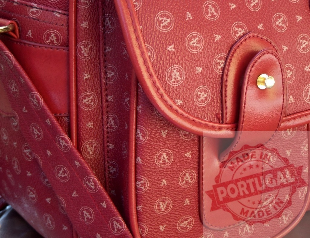 Red leather handbag with gold hardware and logo pattern | Red leather handbag displaying a repeated logo pattern and gold closure detail - Realized with Pictrs.com