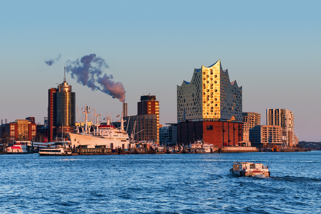 10260305 - HafenCity Skyline im Abendlicht | Blick auf die Elbphilharmonie und die HafenCity mit goldenen Lichtreflexionen der Abendsonne. Kombiniert mit dem traditionellen Museumsschiff Cap San Diego und einer kleinen Hafenbrise im Wasser, fängt dieses Motiv das Herz der Hansestadt perfekt ein - modern, maritim und voller Energie.