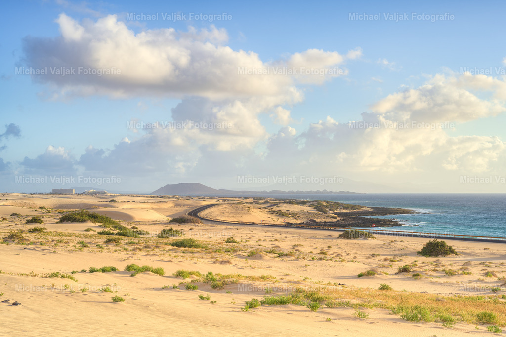 Dünen bei Corralejo auf Fuerteventura | Früher Morgen in den Dünen von Corralejo. Das Licht ist weich, der Sand noch kühl, und die Landschaft wirkt ruhig und weit. Die ersten Schatten zeichnen sanfte Formen in die Dünen, während der Wind nur leicht über die Oberfläche streicht. Ein stiller Moment, der zeigt, wie schön Fuerteventura ganz ohne große Worte sein kann. - Realisiert mit Pictrs.com